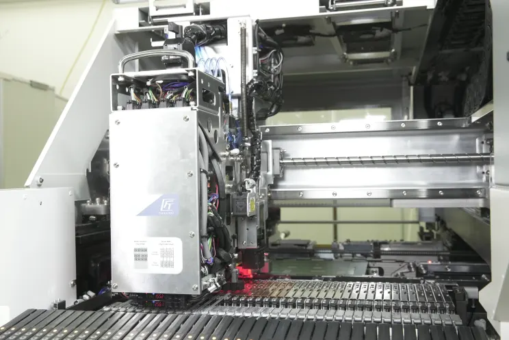 El cabezal TAKUMI de la LX-8 sobre el banco de alimentadores, con la luz roja del láser